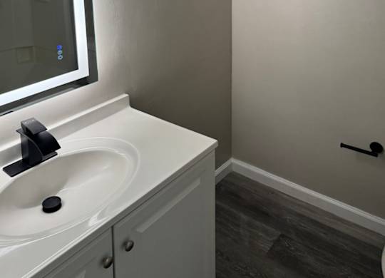 a renovated bathroom with smart mirror, white sink and toilet, and black fixtures