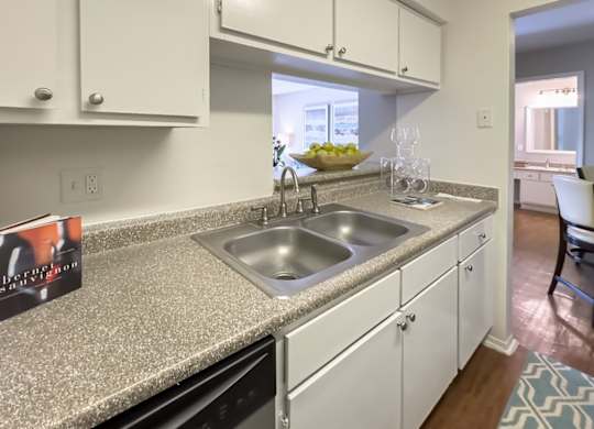 a kitchen with a double stainless steel sink, granite-inspired counter top, and white cabinets