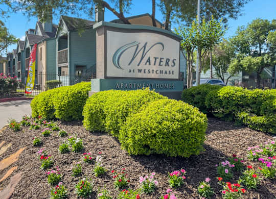 The Waters at Westchase Monument sign surrounded by flowers and lush bushes