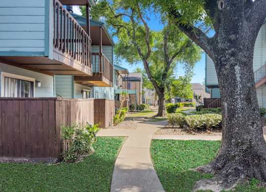 a lush courtyard with neat sidewalks between residential buildings at Waters at Westchase Apartments