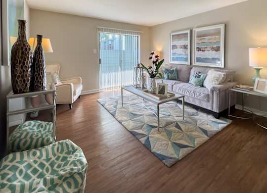 a living room with sliding glass doors and wood-style flooring and model furniture