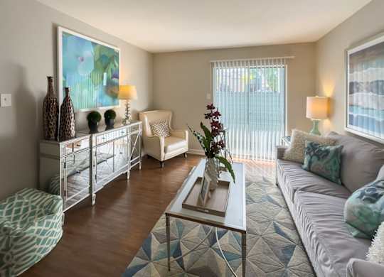 a model living room with wood-like flooring, and large sliding glass doors to a deck
