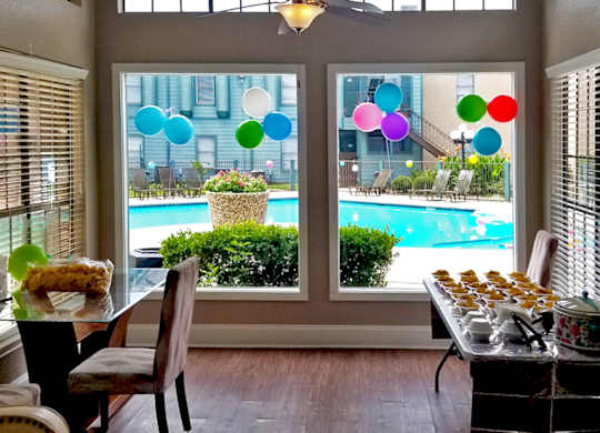 A table with food on it is in front of a window with a view of a pool.