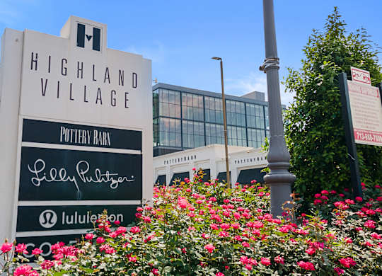 A sign for Highland Village stands in front of a building.