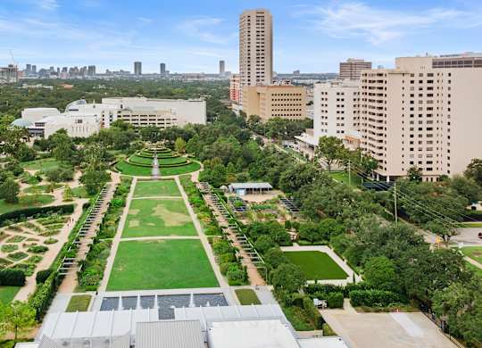 A large green space with a long rectangular lawn in the middle of a city.