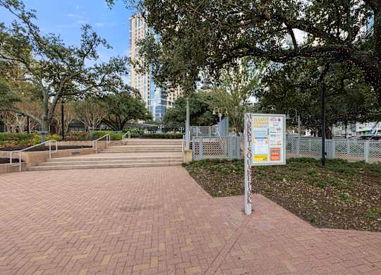 A sign is posted on a post in a park.