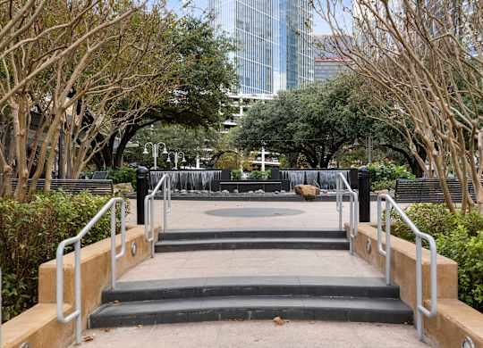 A set of stairs with metal handrails lead down to a water feature in a landscaped area.