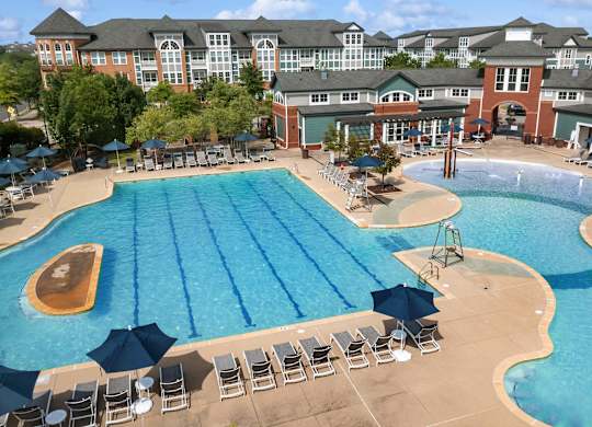 A large swimming pool with a diving board and sun loungers.