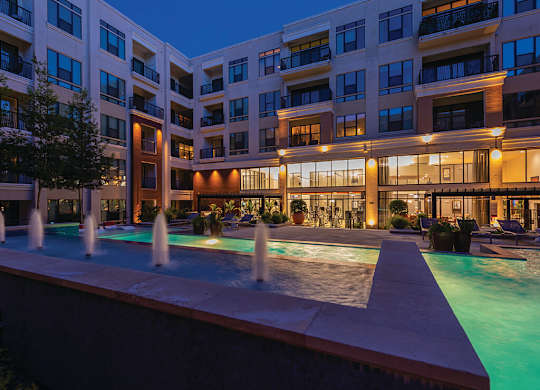 A large building with a pool in front of it.