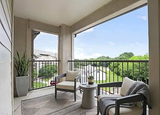 A balcony with a chair, a table, and a potted plant.