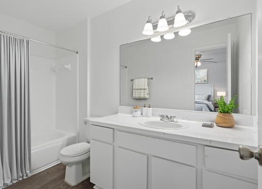 A white bathroom with a toilet, sink, and mirror.