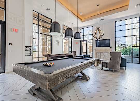 A pool table is in the middle of a room with a television and a chair.