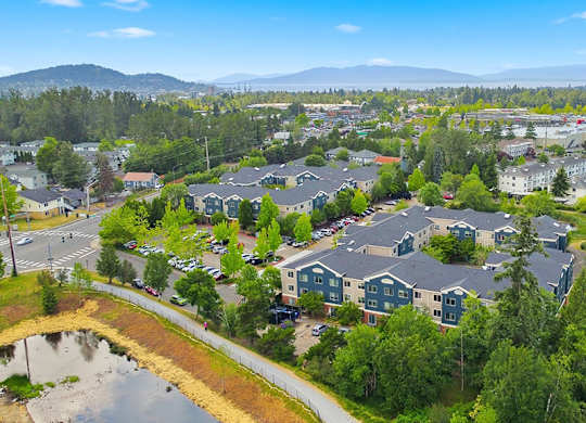 A bird's eye view of a residential area with houses and a pond.