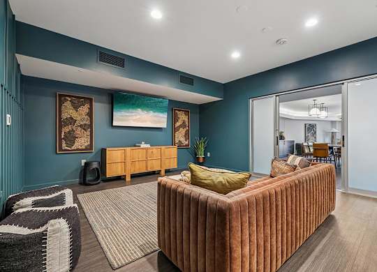 A living room with a brown couch and a painting on the wall.
