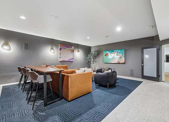 A modern dining area with a blue carpet and a painting on the wall.