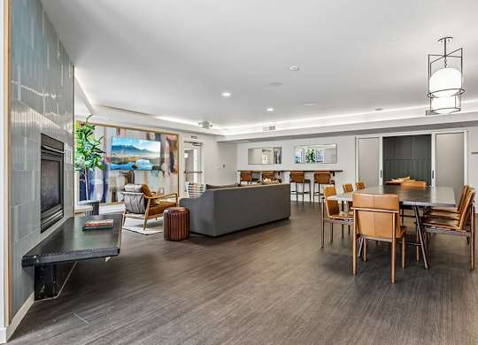 A modern living room with a grey sofa, wooden chairs, and a coffee table.