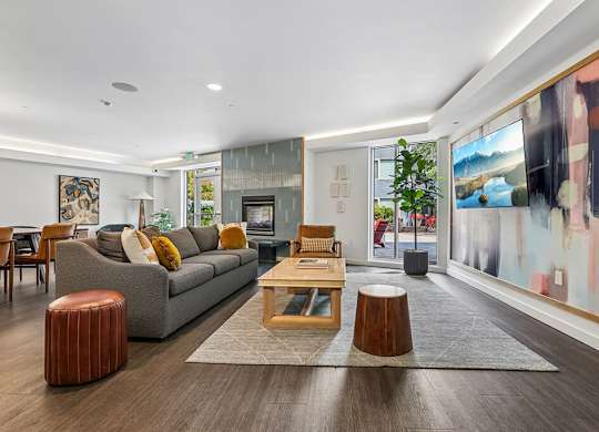 A modern living room with a grey sofa, wooden coffee table, and a large abstract painting on the wall.