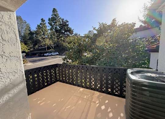 A balcony with a black railing and a wall-mounted air conditioning unit.