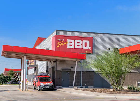 A red and white True BBQ Jax restaurant with a red truck parked in front.