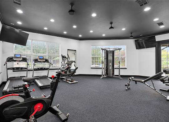 A spacious gym with a variety of exercise equipment including treadmills, stationary bikes, and weight machines.