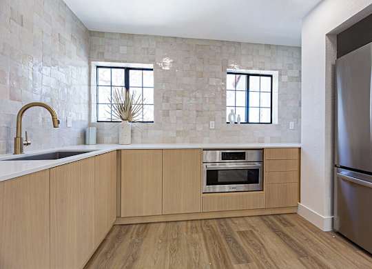 A kitchen with wooden cabinets and a stainless steel refrigerator.