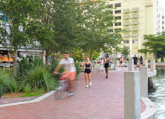 A woman is running on a brick pathway next to a body of water.