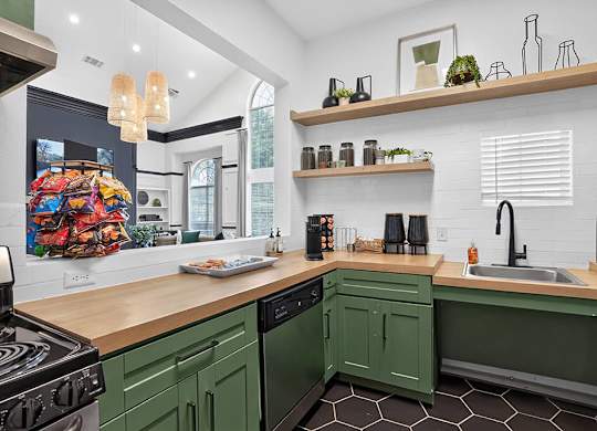 A kitchen with green cabinets and a wooden counter.