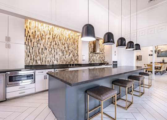 A modern kitchen with a dark countertop and stools.