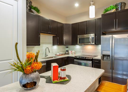 A kitchen with a white counter top and black cabinets.