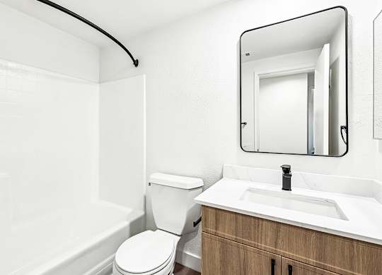 A white bathroom with a toilet, sink, and mirror.