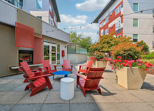 A patio with red chairs and a table.
