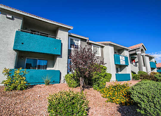 an apartment building with blue balconies and a landscaped yard