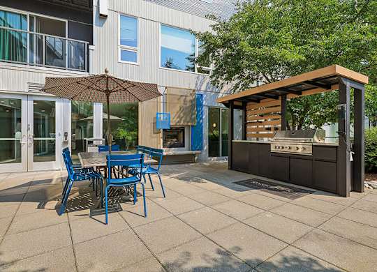 A patio with a table and chairs and a grill.