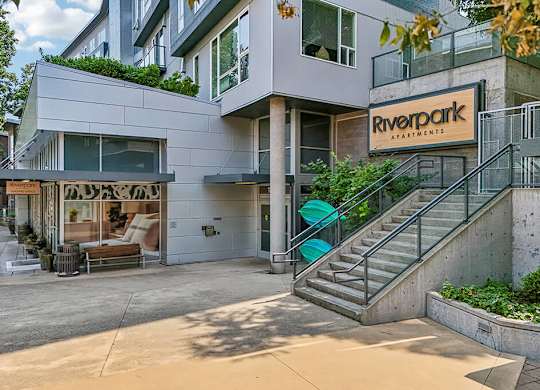 A modern building with the sign "Riverpark Apartments" on the front.