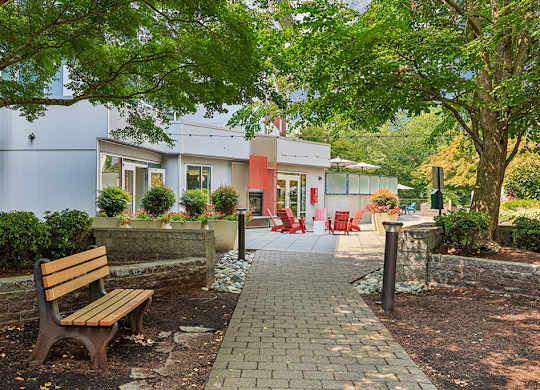 A wooden bench sits in front of a building with a red door.