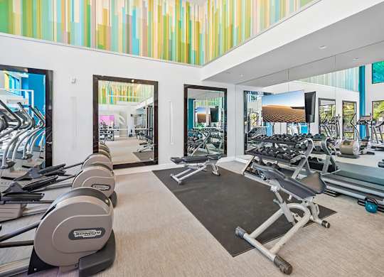 A gym with a variety of equipment including treadmills, weights, and exercise machines.