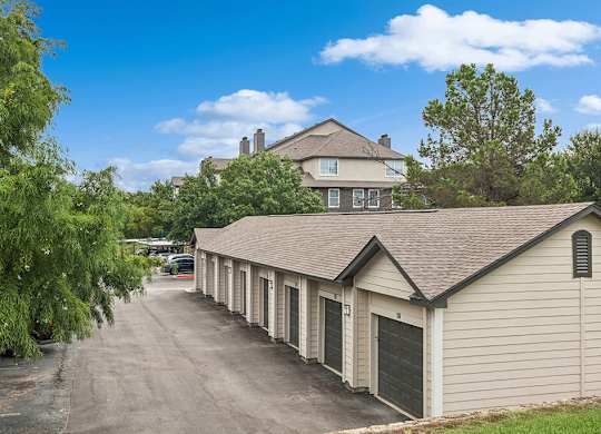 A row of garages are in front of a house.