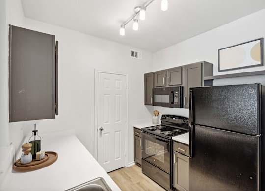 A black refrigerator is in a kitchen with a white door.