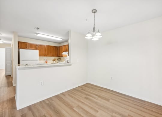 an empty living room and kitchen with wood flooring