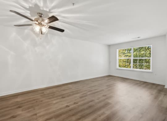 an empty living room with a ceiling fan and a window
