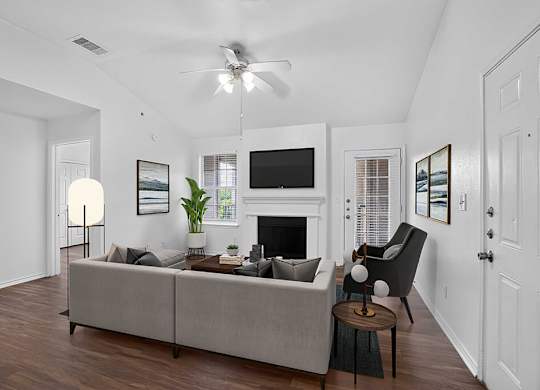A living room with a grey couch, a fireplace, and a television.
