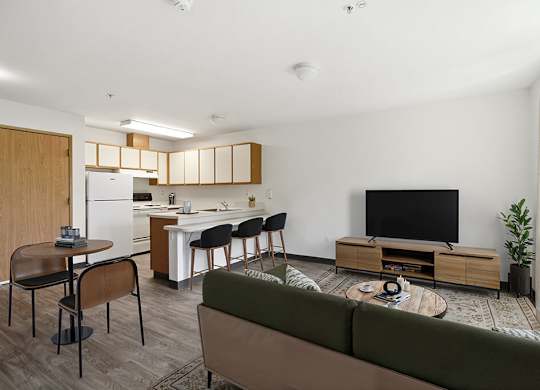 A modern living room with a green sofa, a wooden coffee table, and a television.