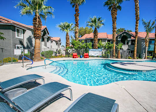 a swimming pool with two chairs and palm trees