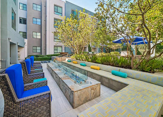 A patio with blue chairs and a table with a glass top.