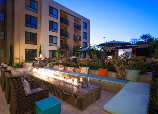 A patio with a long bench and a fire pit.