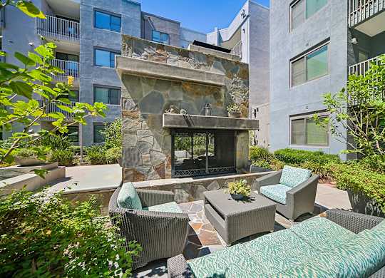 A patio with a fireplace and chairs.