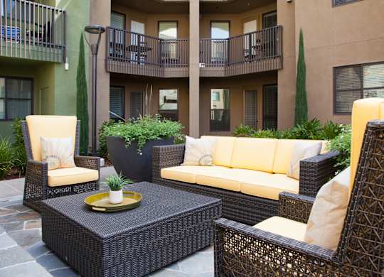 A patio with a sofa, chairs and a table.