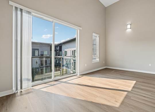 A room with a large sliding glass door and wooden flooring.