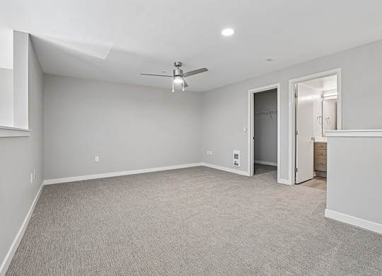 A spacious room with a ceiling fan and carpeted floor.