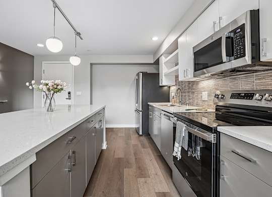 A modern kitchen with stainless steel appliances and wooden floors.